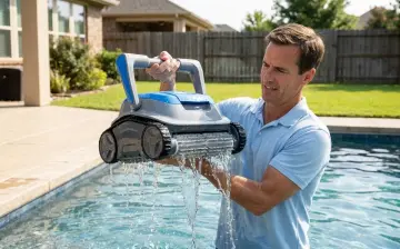 Un propriétaire sort son robot de piscine de l'eau, les chenilles ruisselantes