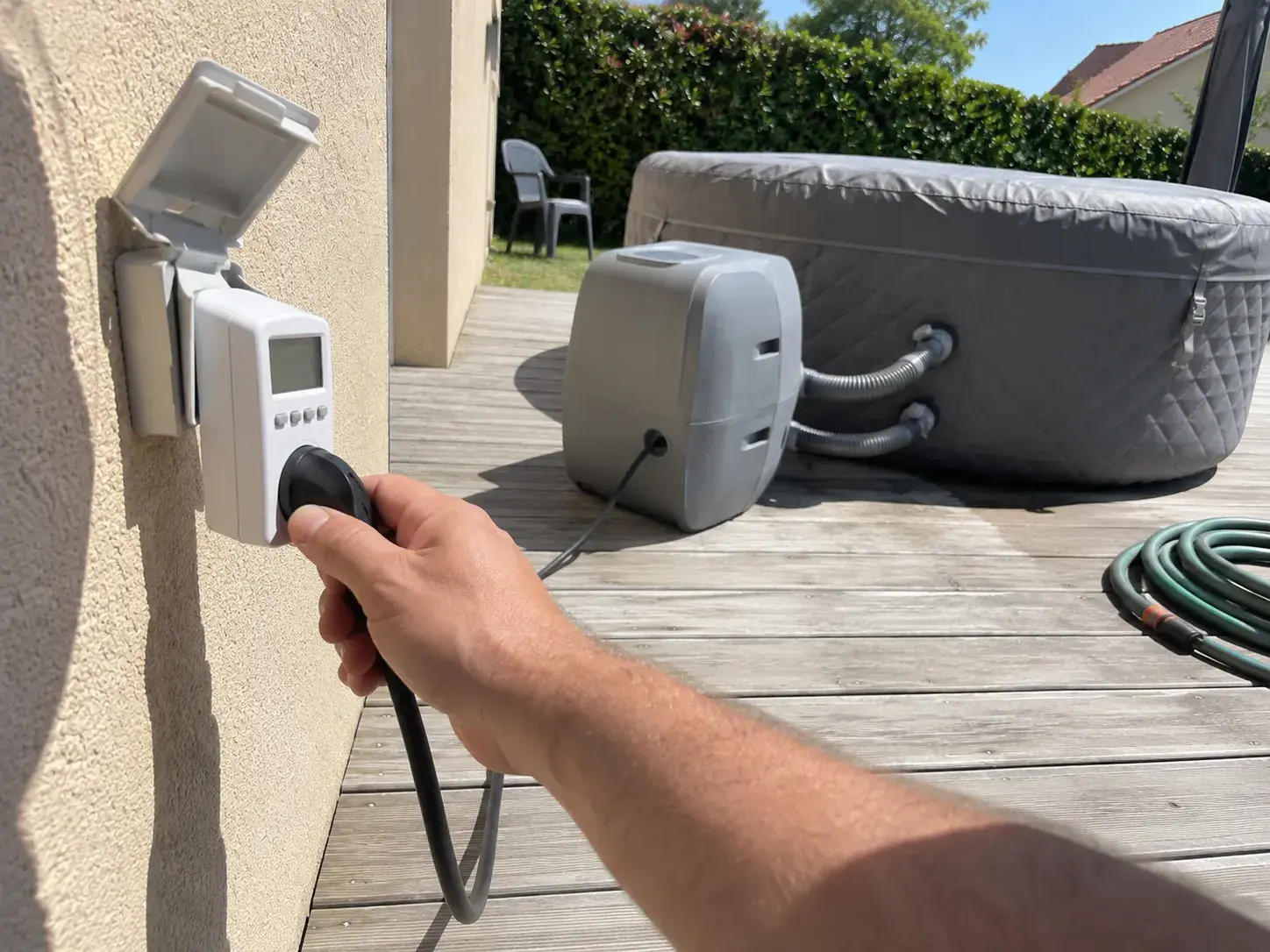 Le câble du spa branché sur un wattmètre de prise, au mur de la maison