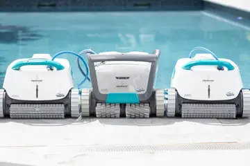 Trois robots Dolphin filaires alignés sur la margelle, câbles bleus dans l'eau