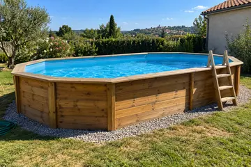 Une piscine bois octogonale allongée sur la pelouse, ses madriers au soleil