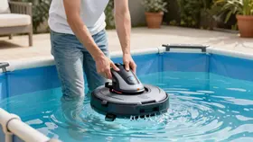 Un propriétaire pose son robot dans l'eau d'une piscine tubulaire, par-dessus la paroi