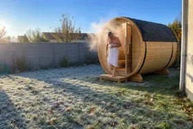 Un homme en serviette sort du sauna tonneau, la vapeur dans le froid du matin