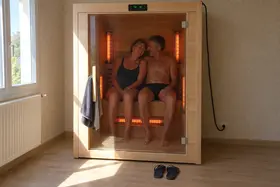 Un couple épaule contre épaule dans une cabine infrarouge, la porte fermée, les tubes allumés