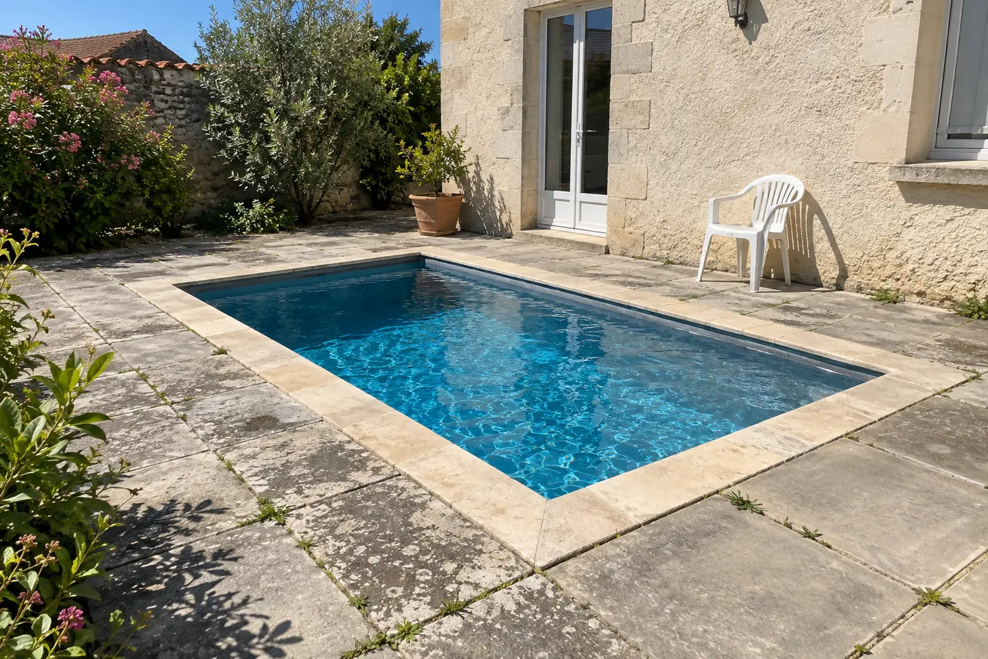 Une toute petite piscine enterrée, prise dans la terrasse dallée contre la maison